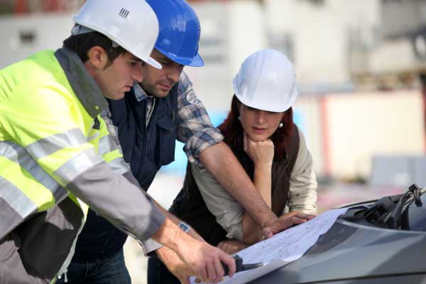 Construction team on site having meeting on bonnet of vehicle