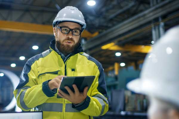 Engineer on tablet inside industrial factory