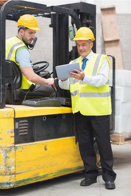 Forklift driver talking with his trainer in warehouse.